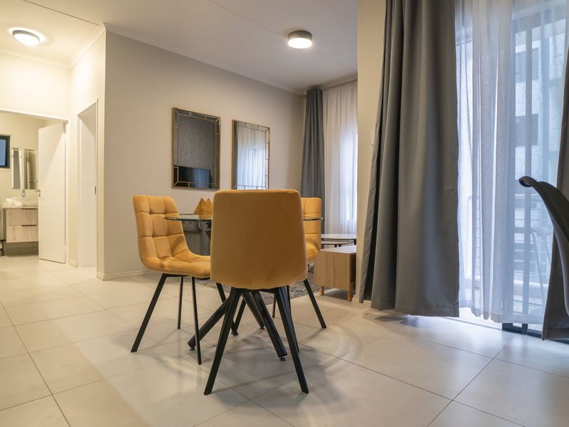Modern open-plan living area featuring tiled flooring, recessed lighting, and a sliding glass door leading to an outdoor space.