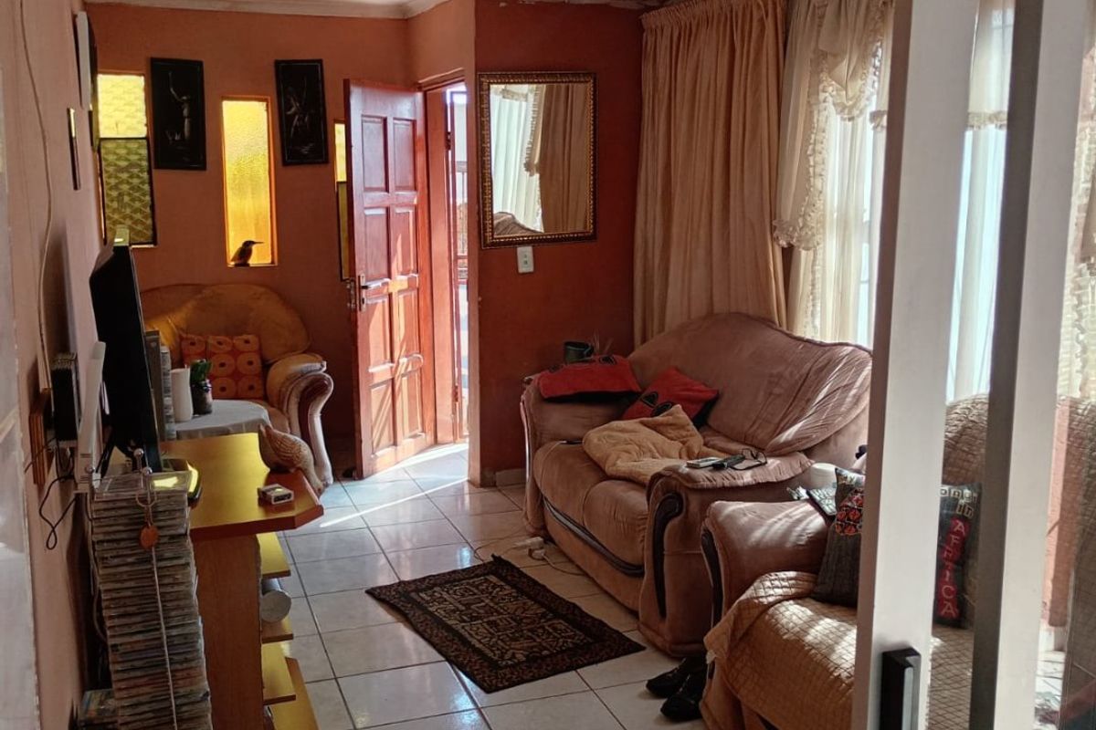 A living room featuring ceramic floor tiles, recessed wall niches, and access via a sliding glass door, offering a functional layout for relaxation.