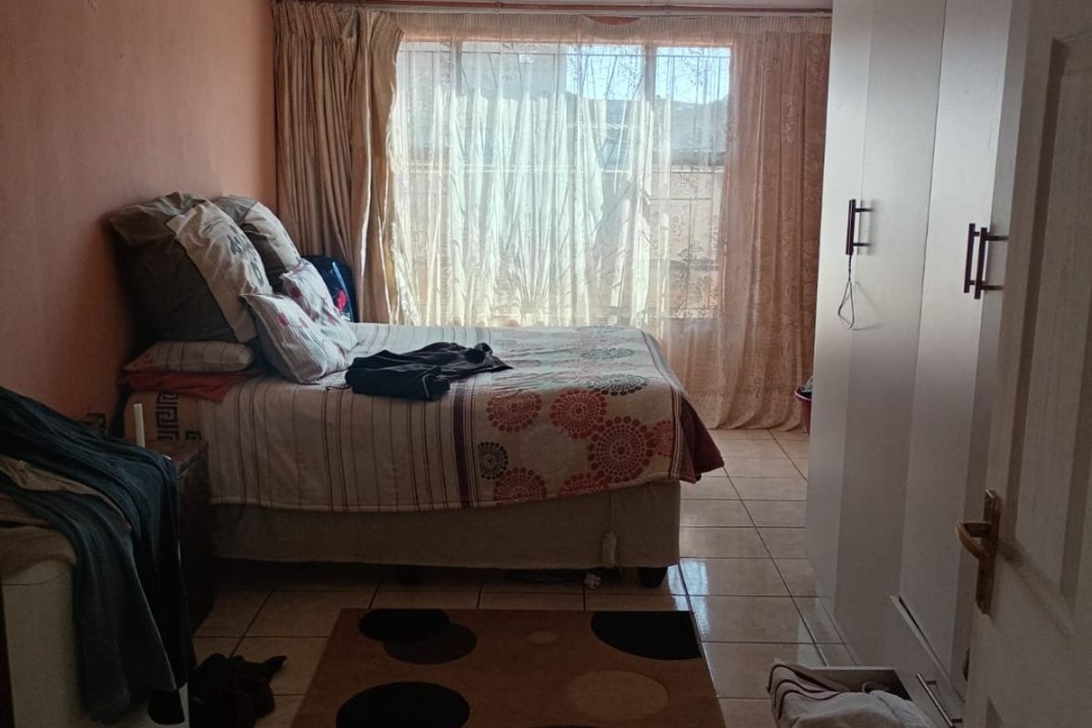 A bedroom featuring tiled flooring, a built-in wardrobe, and a corrugated ceiling, offering a functional space with potential for cosmetic updates.