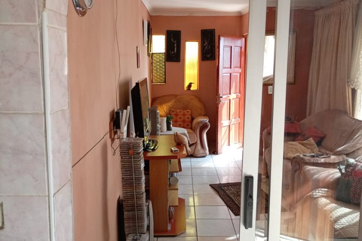 A living room area featuring tiled flooring, an arched entryway, and a sliding glass door leading to an adjacent space with recessed wall niches.