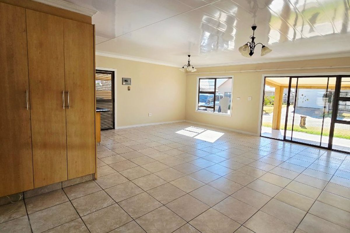 Spacious, light-filled living area featuring neutral tiled flooring, built-in storage cabinetry, and large sliding glass doors providing seamless access to the outdoor patio.