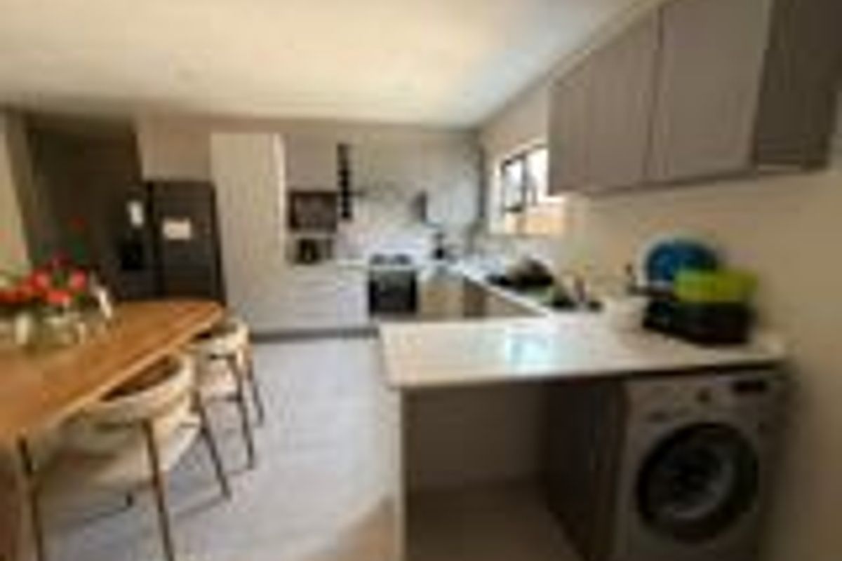 A functional kitchen featuring modern cabinetry, stone countertops, a breakfast bar, and integrated appliances, offering a clean and practical layout.