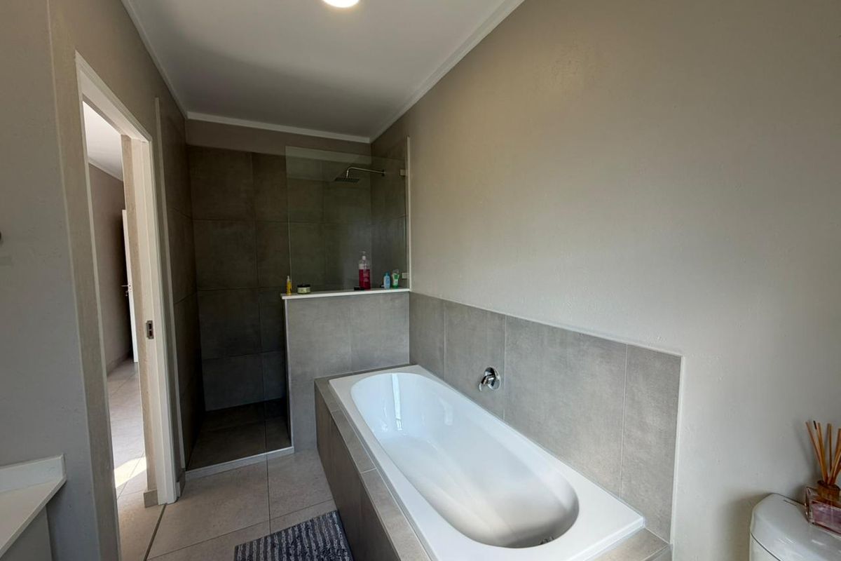 Modern bathroom featuring a built-in bathtub, a separate walk-in shower with a glass screen, and neutral-toned wall and floor tiling.