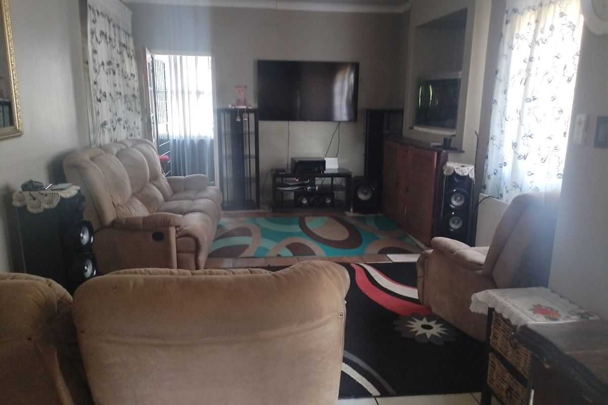 A comfortable living room featuring tiled flooring, decorative cornicing, and a built-in wall niche for media storage.