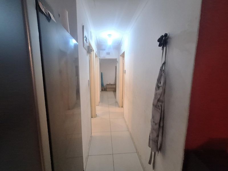 A narrow residential hallway featuring tiled flooring and neutral wall finishes, providing access to multiple rooms within the apartment.