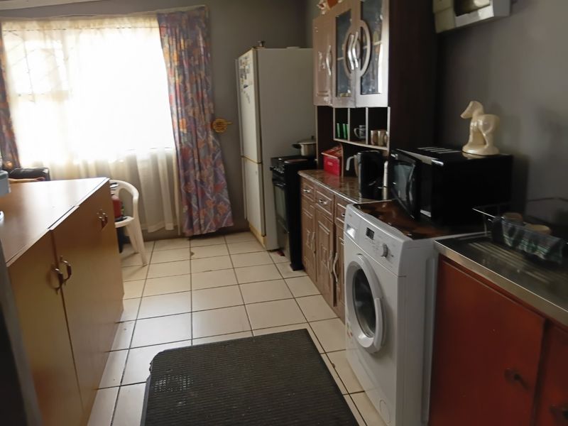 A functional kitchen featuring tiled flooring, built-in cabinetry, and a freestanding stove, offering potential for modernization and aesthetic updates.