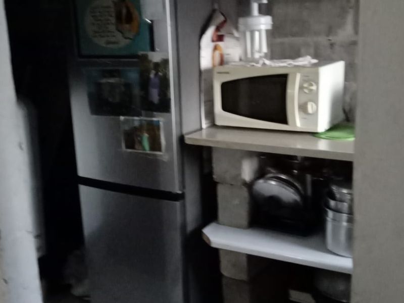 A small utility or scullery area featuring exposed concrete block walls and tiled flooring, providing basic storage and prep space.