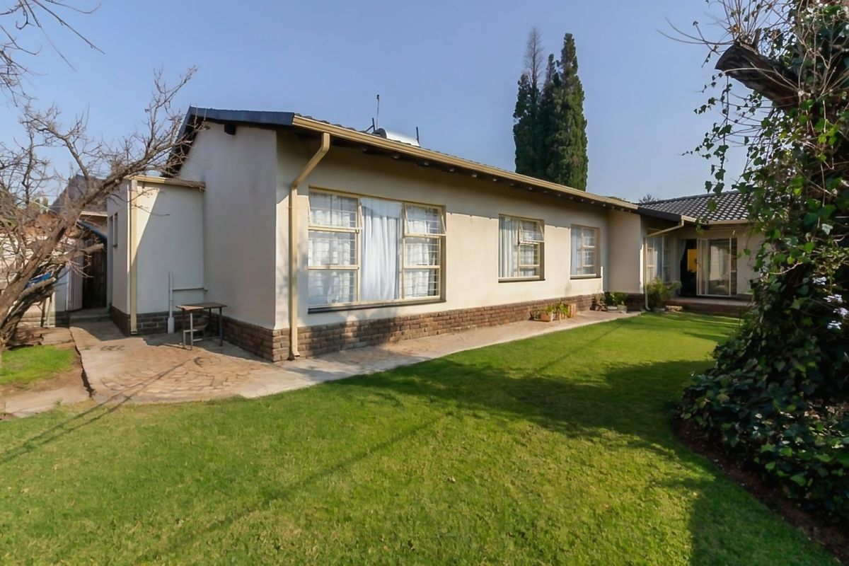 Rear view of the house featuring a lawn, paved walkway, brick plinth, and solar geyser installation on the roof.