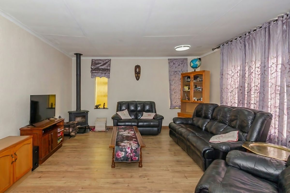 A spacious living room featuring laminate flooring and a freestanding fireplace, offering a comfortable and functional layout for relaxation.