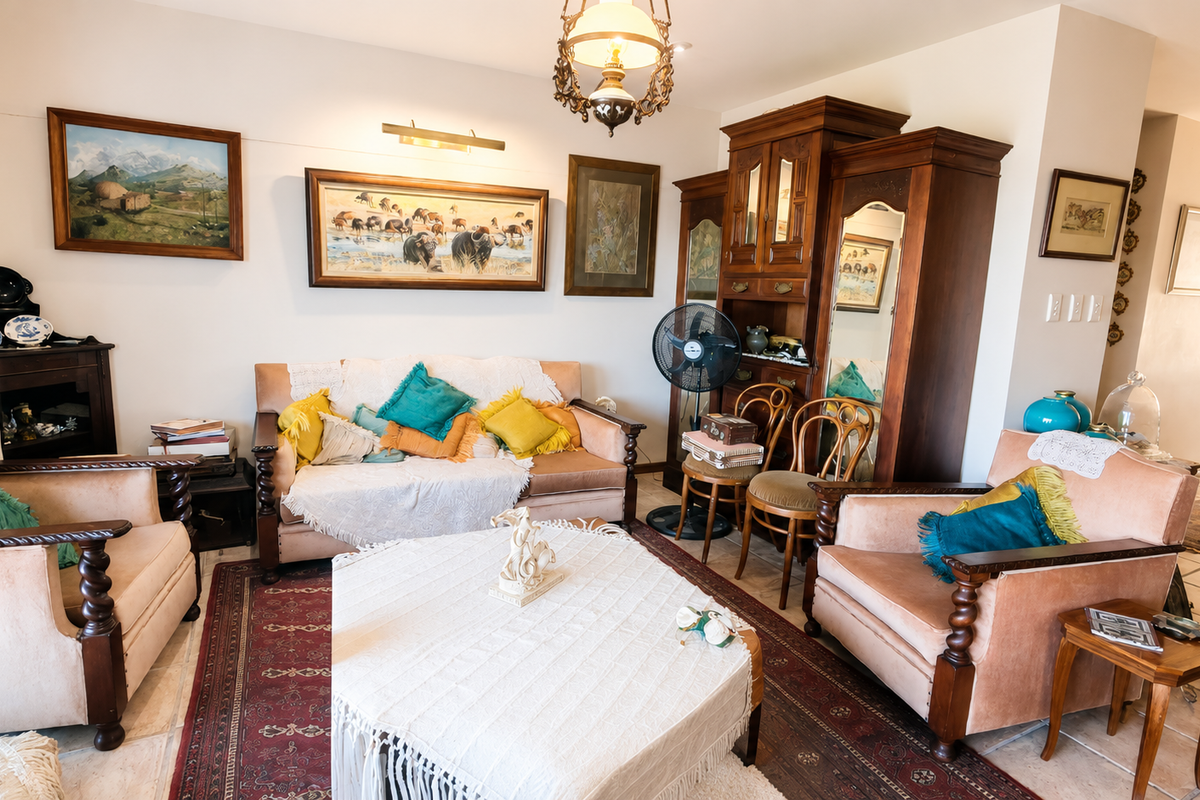 A traditional living room featuring tiled flooring, an ornate chandelier, and a picture light, offering a classic and cozy atmosphere.