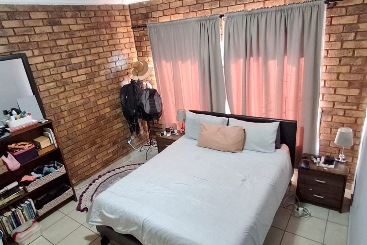 A bedroom featuring an exposed brick feature wall and tiled flooring, providing a rustic aesthetic.