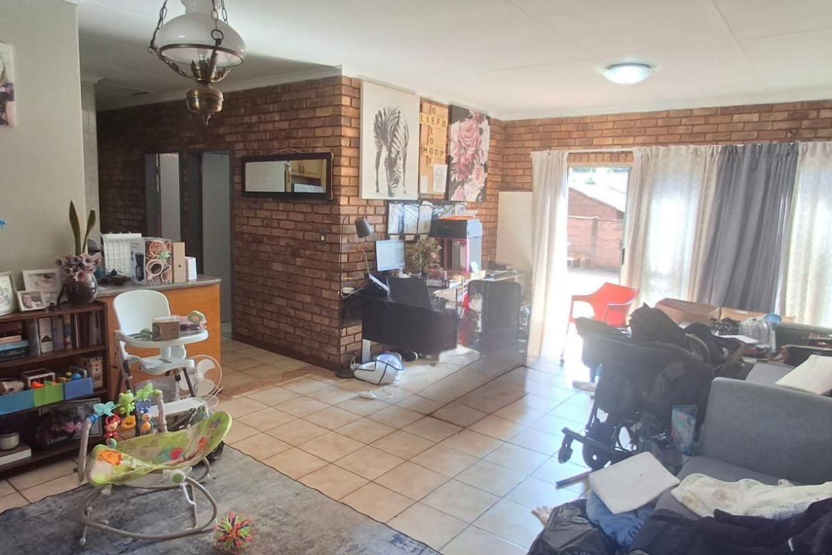 A living room featuring exposed brick walls and ceramic floor tiles, with a sliding glass door providing access to the exterior.