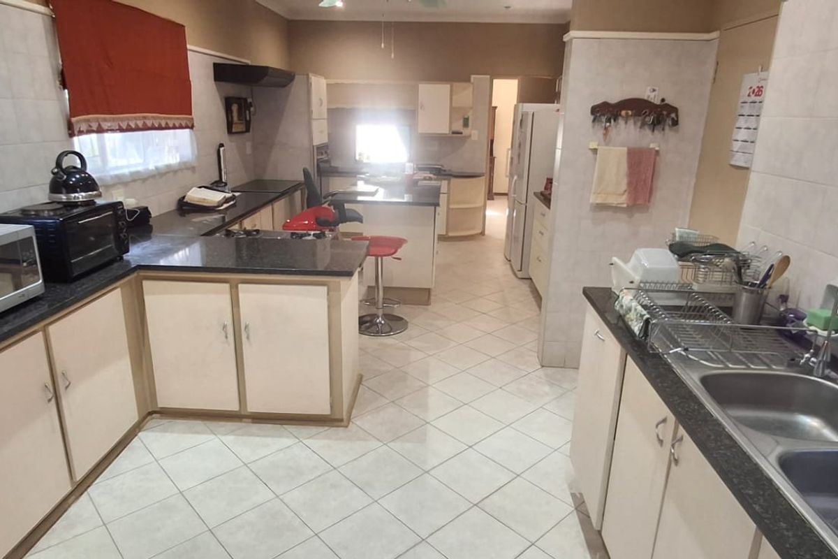 Spacious kitchen featuring granite countertops, extensive built-in cabinetry, double bowl stainless steel sink, and ceramic floor tiling.