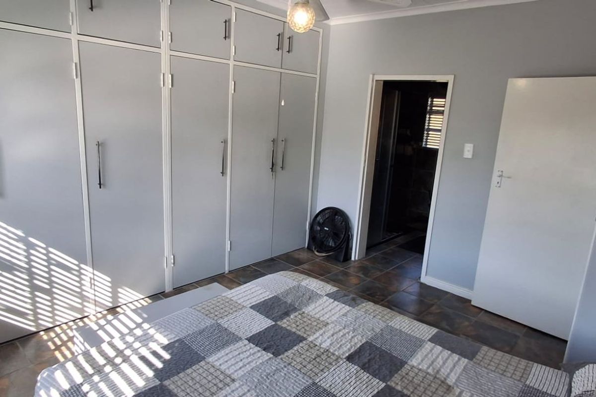 A bedroom featuring extensive built-in cupboards, tiled flooring, and direct access to an adjoining room.