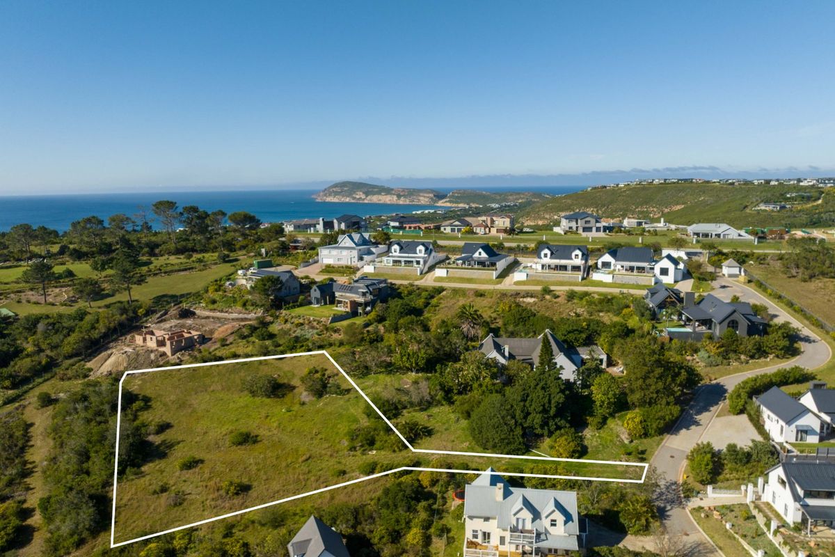 An aerial view of a vacant residential plot situated in a coastal estate, showcasing the surrounding neighborhood and ocean views.