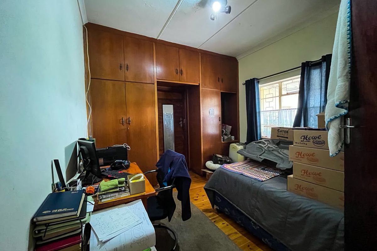 A bedroom featuring built-in wooden cupboards and wooden flooring, offering functional storage space with potential for cosmetic updates.
