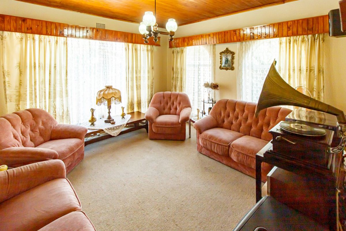A traditional living room featuring a warm timber-paneled ceiling, timber cornice detailing, and neutral carpet flooring, offering a classic and cozy atmosphere.