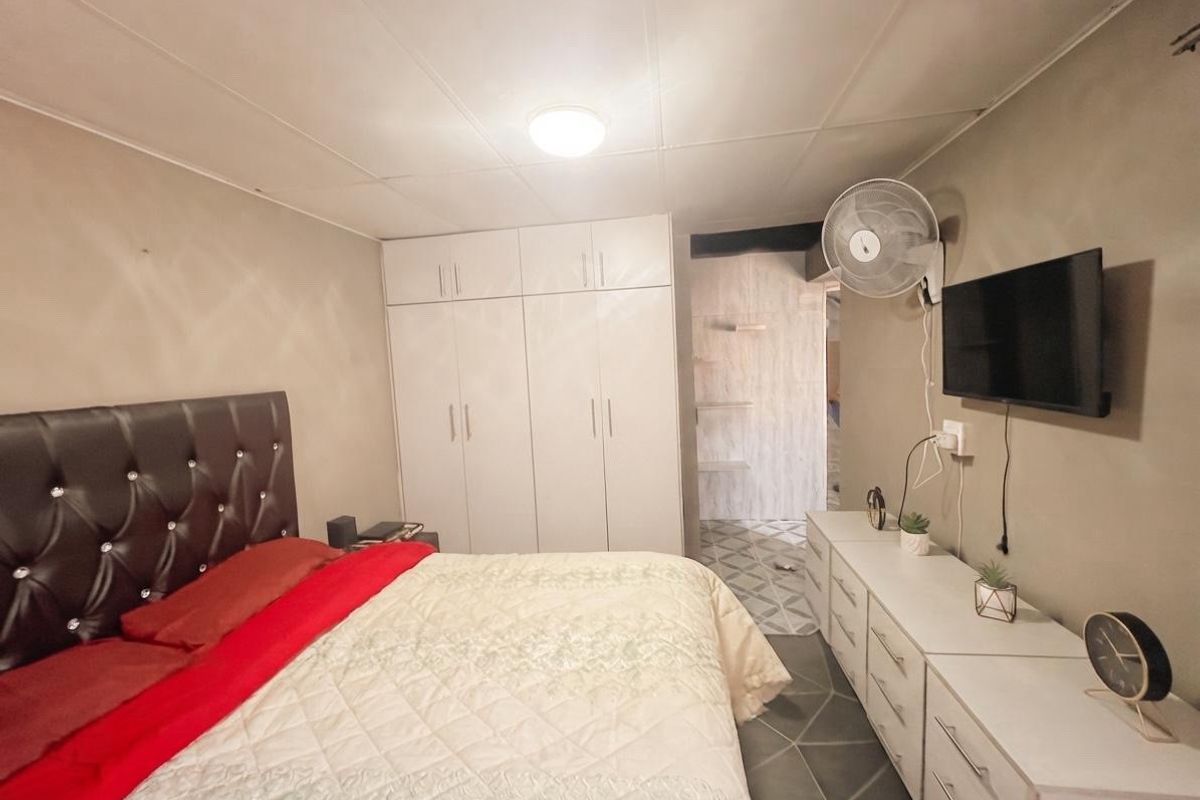 A functional bedroom featuring built-in wardrobes, tiled flooring, and a neutral wall finish, providing a practical and comfortable sleeping space.