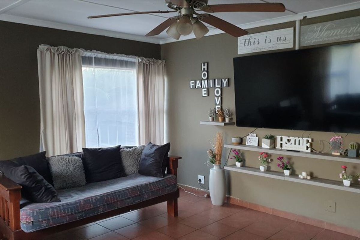 A comfortable living room featuring tiled flooring, a ceiling fan, and built-in floating shelves for display.