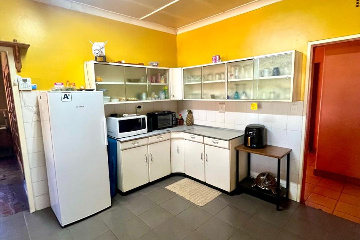 A functional kitchen featuring built-in cabinetry, tiled flooring, and a tiled backsplash, offering a dated aesthetic ready for modernization.