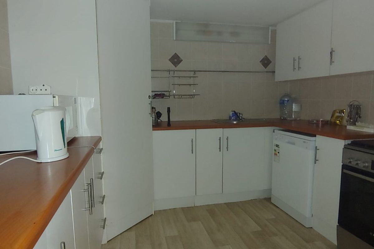 A functional kitchen featuring white cabinetry, laminate countertops, tiled backsplash, and integrated appliances, offering a clean and practical workspace.