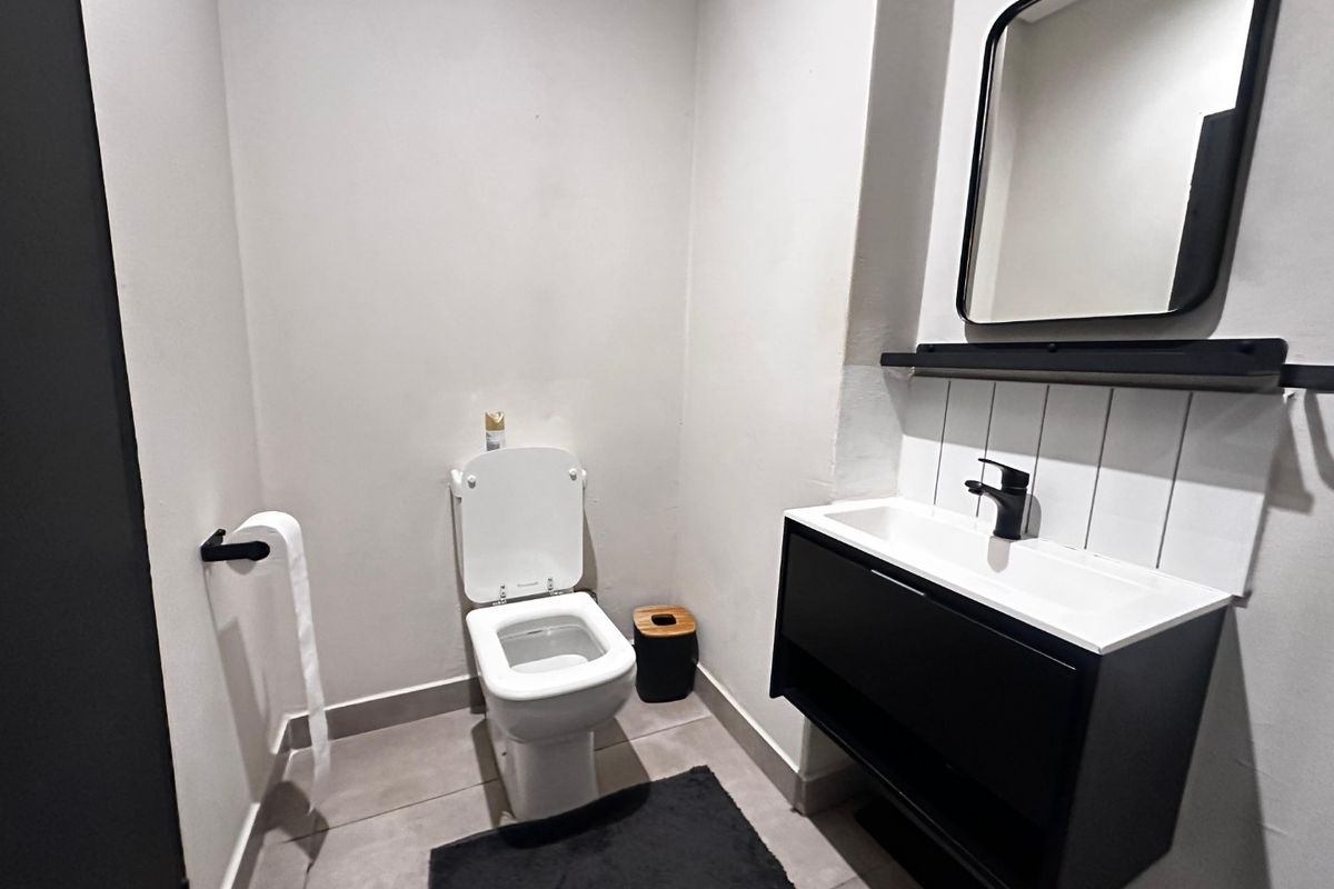 A modern, compact bathroom featuring a sleek vanity with basin, contemporary black fixtures, and a minimalist mirror.