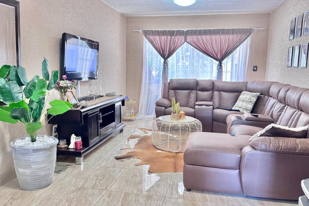 A comfortable living room featuring tiled flooring and textured wall finishes, providing a functional and neutral space for relaxation.
