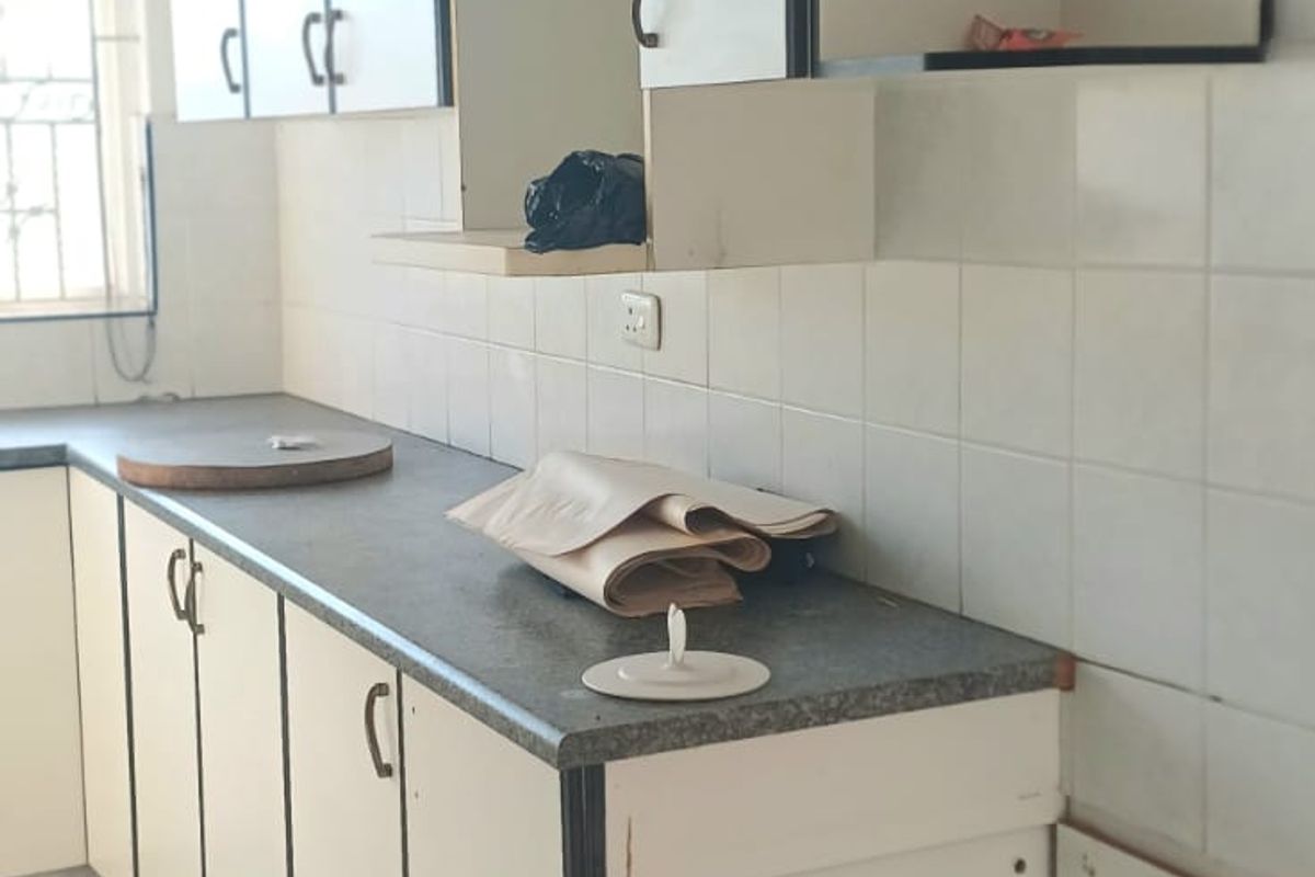 A functional kitchen featuring white built-in cabinetry with dark trim, laminate countertops, and tiled splashbacks. The space is ready for a modern update.