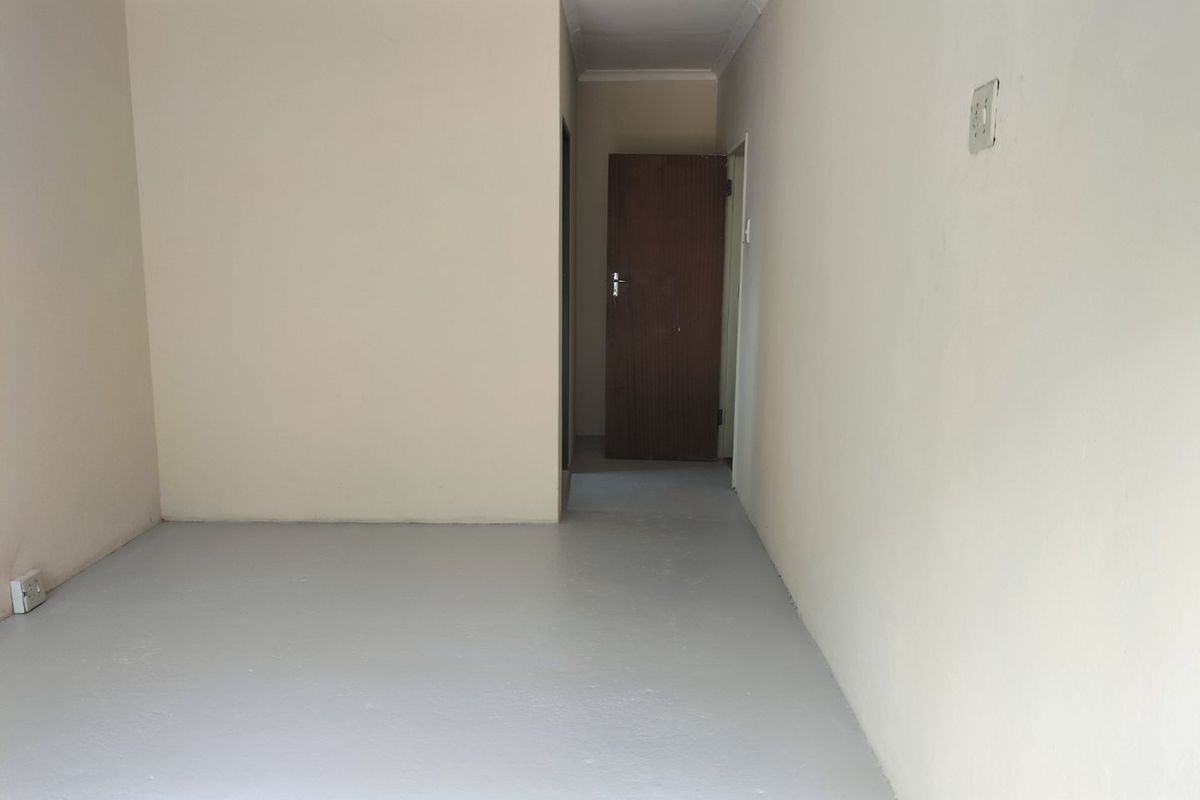 An empty, neutral-toned living area featuring painted concrete flooring and simple architectural finishes, ready for personalization.