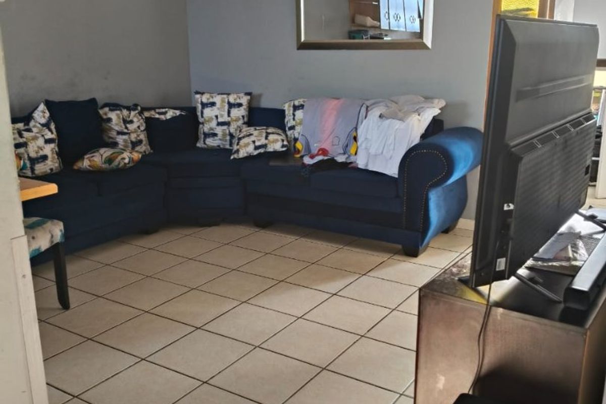 A living room area featuring neutral tiled flooring and grey painted walls, providing a functional space for relaxation.