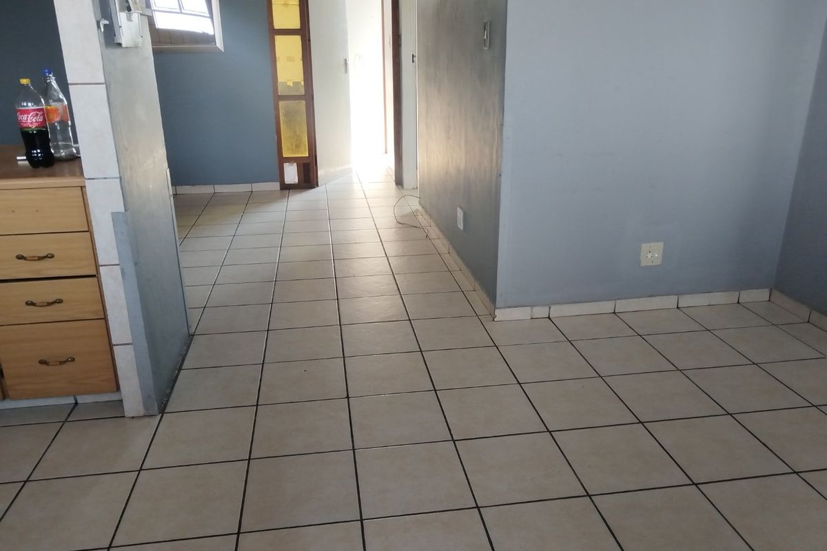 An empty living area featuring ceramic floor tiles and neutral wall paint, providing a blank canvas for potential interior design updates.