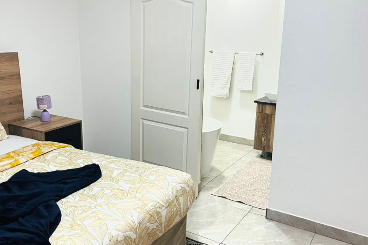 A well-maintained bedroom featuring tiled flooring, coved ceilings, and a sliding barn door providing access to an en-suite bathroom.