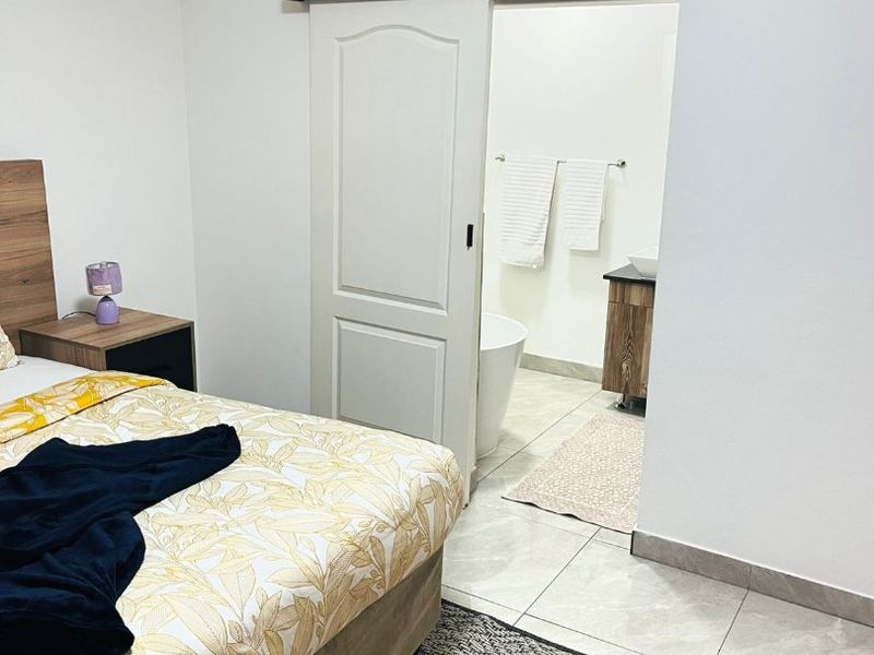 A well-maintained bedroom featuring tiled flooring, coved ceilings, and a sliding barn door providing access to an en-suite bathroom.
