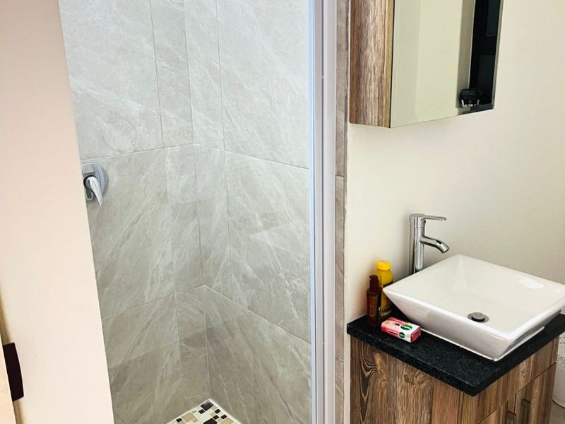 Modern bathroom featuring a glass-enclosed shower with rain shower head, a vessel sink vanity, and a mirrored medicine cabinet.