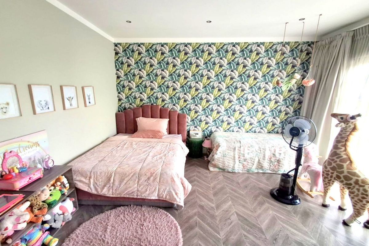 A spacious bedroom featuring stylish herringbone flooring, recessed downlighting, and a decorative feature wall with botanical wallpaper.
