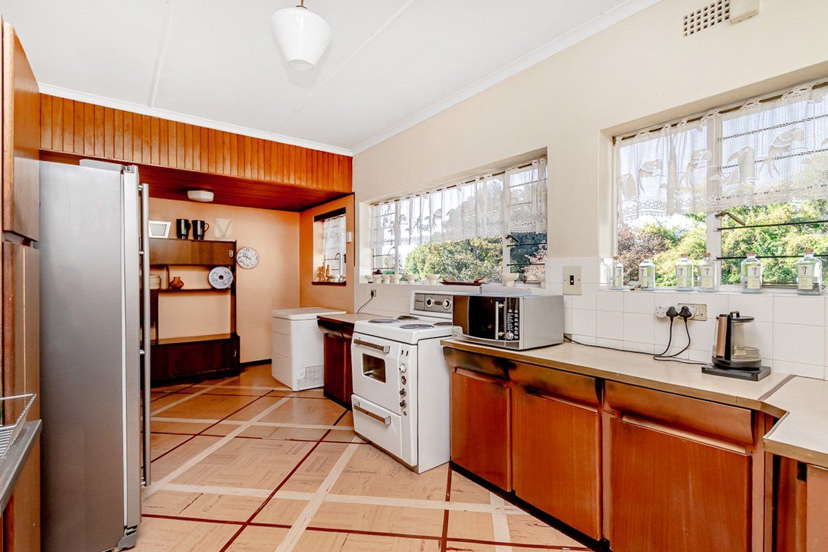 A functional kitchen featuring wooden cabinetry, tiled backsplash, and a freestanding oven, offering a dated aesthetic with potential for modernization.