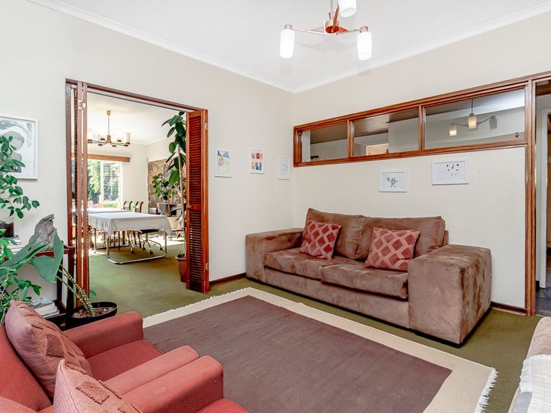 A living room featuring wooden folding doors leading to an adjacent dining area and internal clerestory windows providing natural light flow.