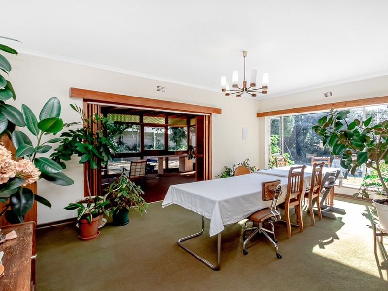 Spacious dining room featuring timber bi-fold doors opening to an outdoor area, large windows, and neutral wall finishes.