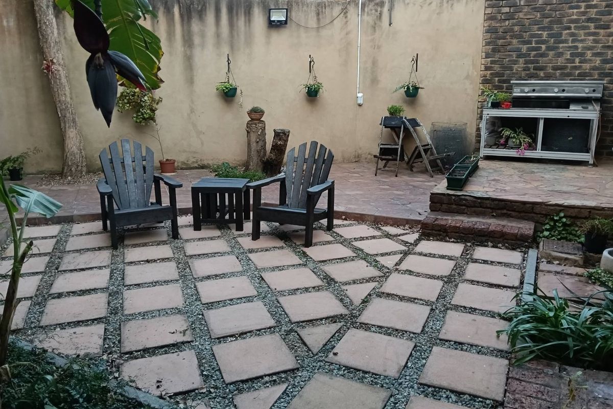 A private rear courtyard featuring a paved patio area, built-in braai, and high boundary walls, offering a functional outdoor entertainment space.