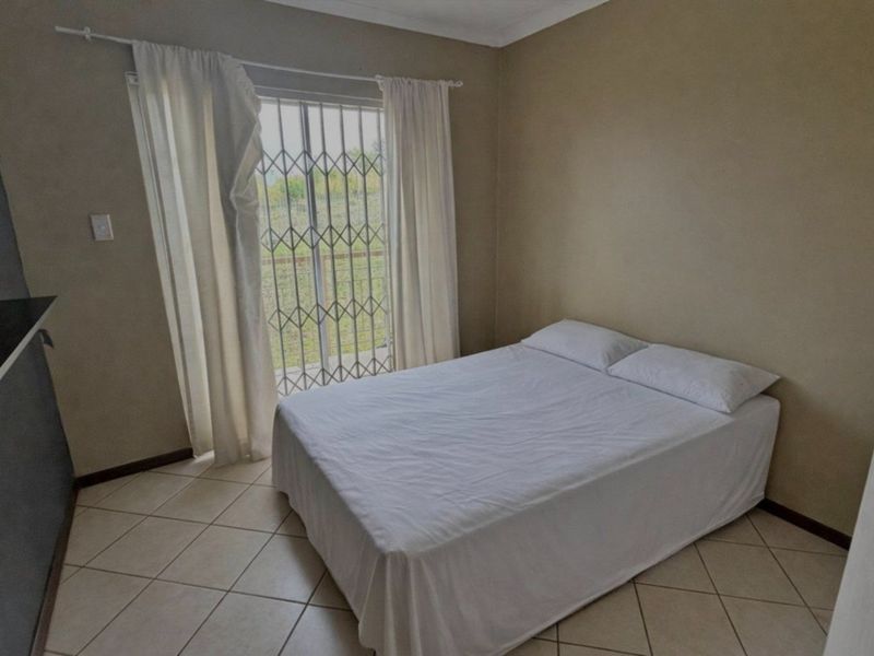 A bedroom featuring tiled flooring, a built-in cupboard, and a sliding glass door with a security gate providing access to the outdoors.