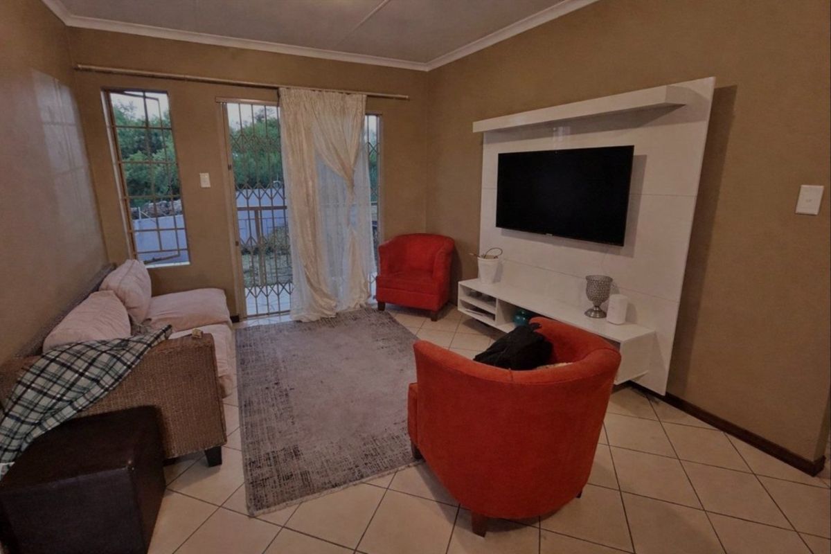 A living room featuring tiled flooring, a built-in media unit, and a security gate leading to an outdoor area.