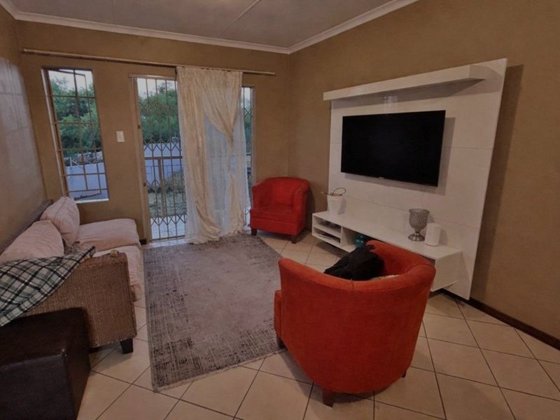 A living room featuring tiled flooring, a built-in media unit, and a security gate leading to an outdoor area.
