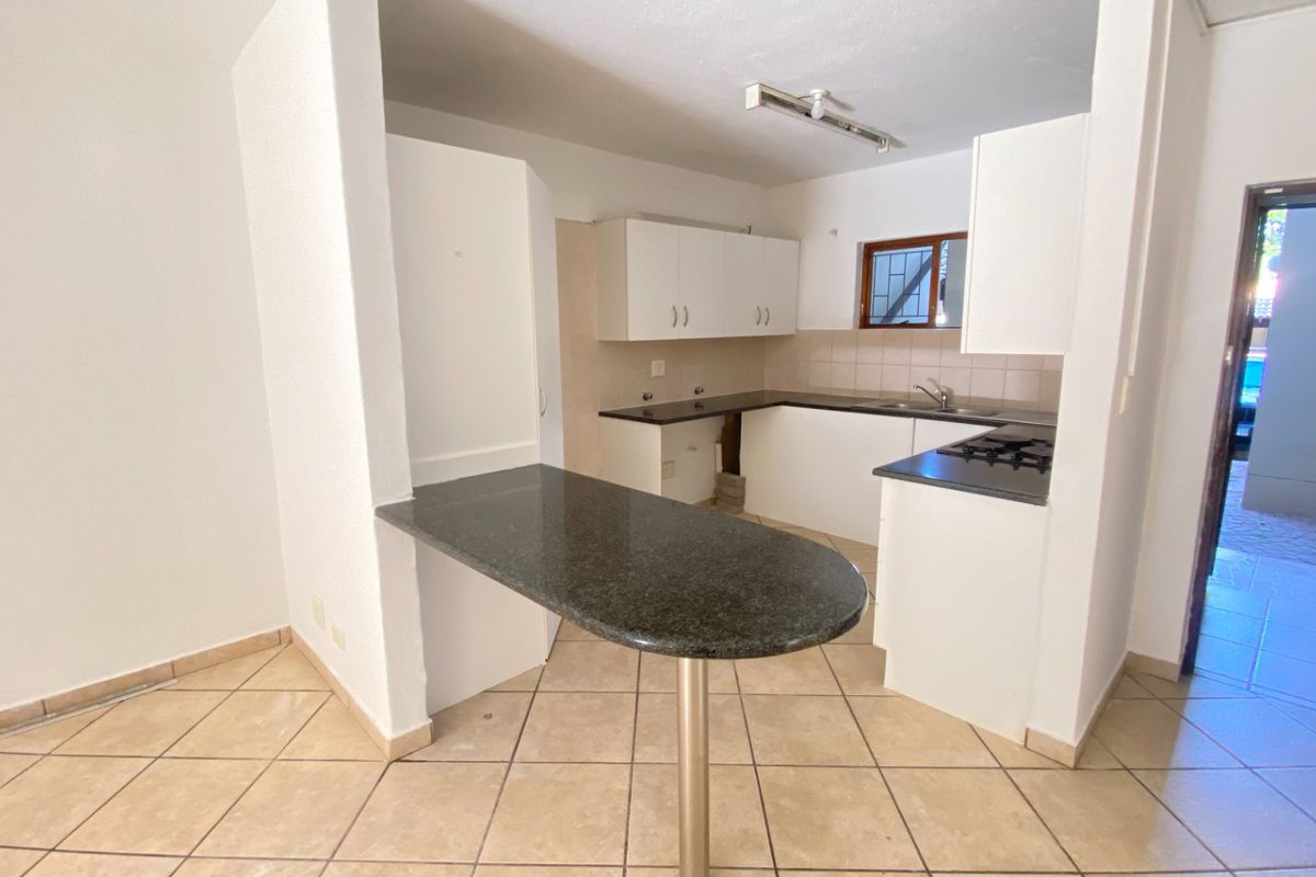 A functional kitchen featuring granite countertops, a breakfast bar, built-in gas hob, and tiled flooring, offering a blank canvas for modern updates.