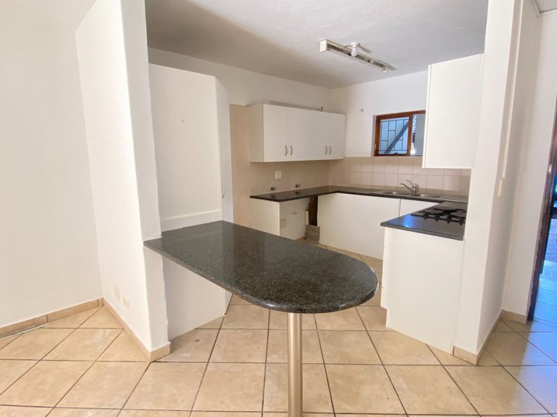 A functional kitchen featuring granite countertops, a breakfast bar, built-in gas hob, and tiled flooring, offering a blank canvas for modern updates.