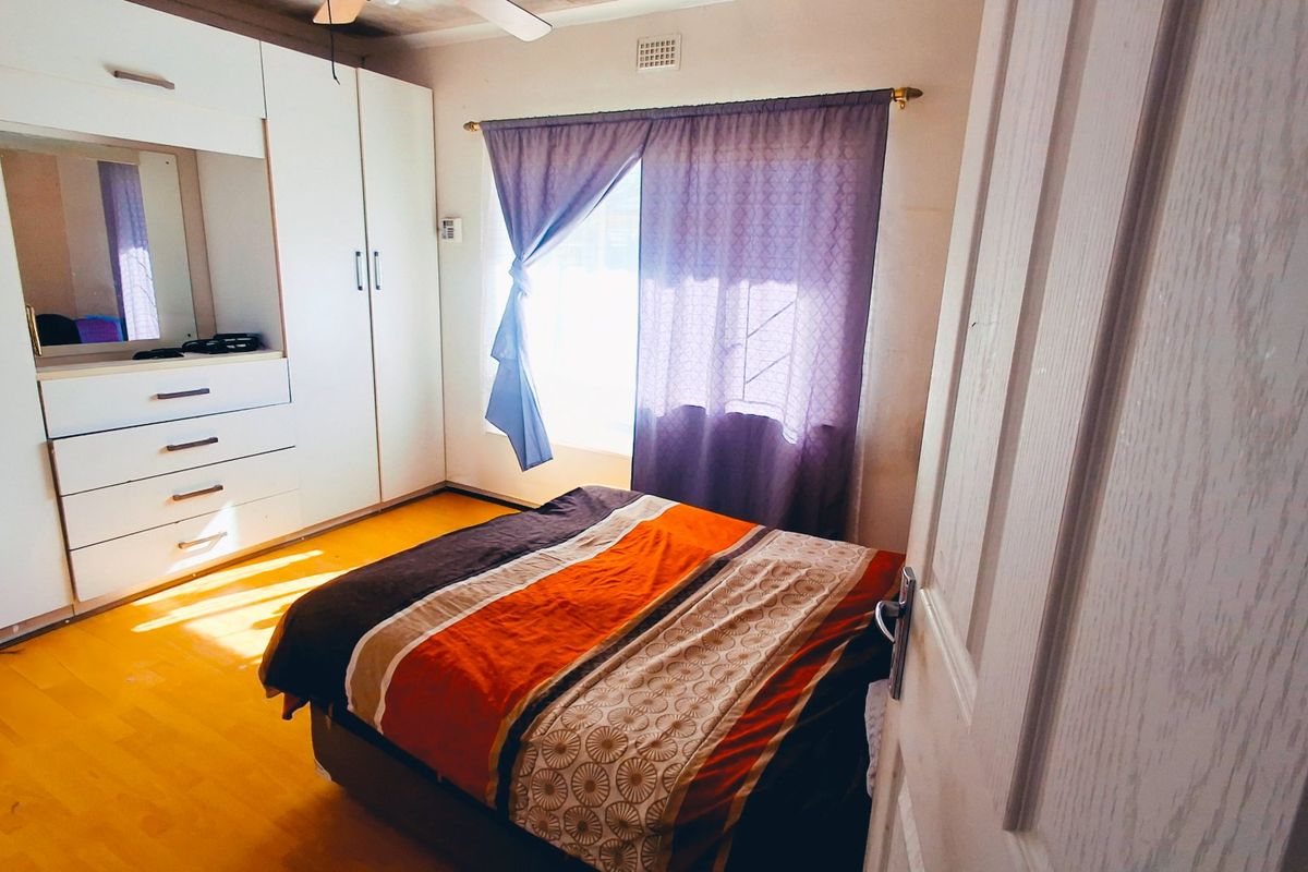 A bedroom featuring laminate flooring, a built-in wardrobe with integrated vanity, and a ceiling fan.