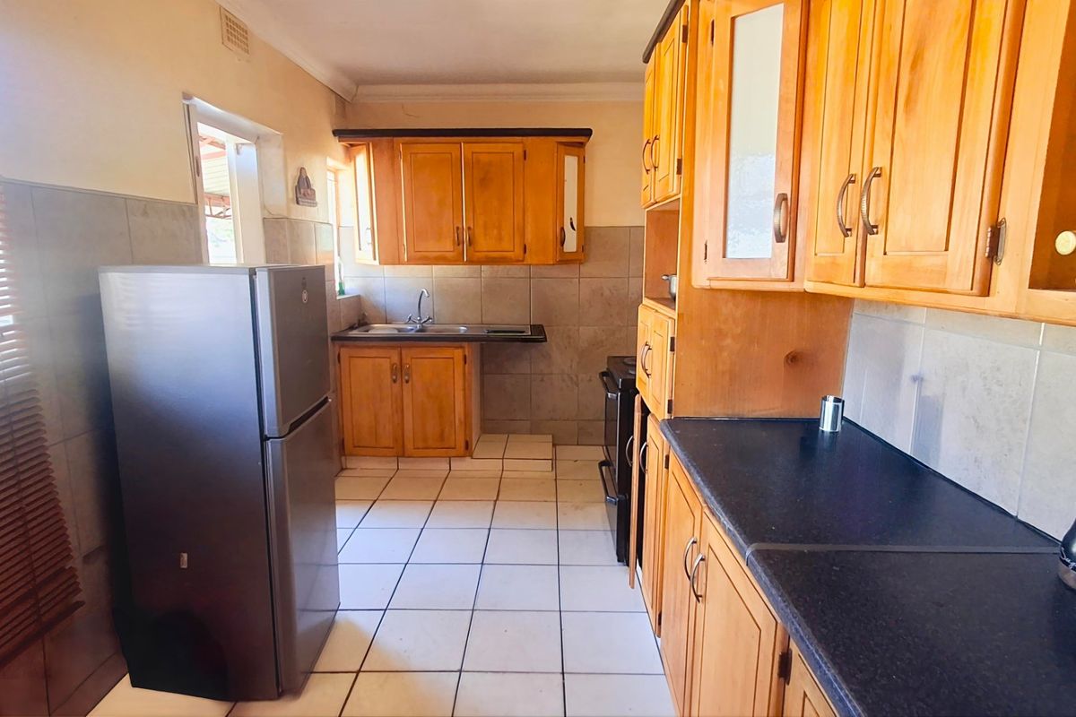 A functional kitchen featuring wooden cabinetry, tiled backsplash, and ample counter space, offering a classic layout with potential for modern updates.
