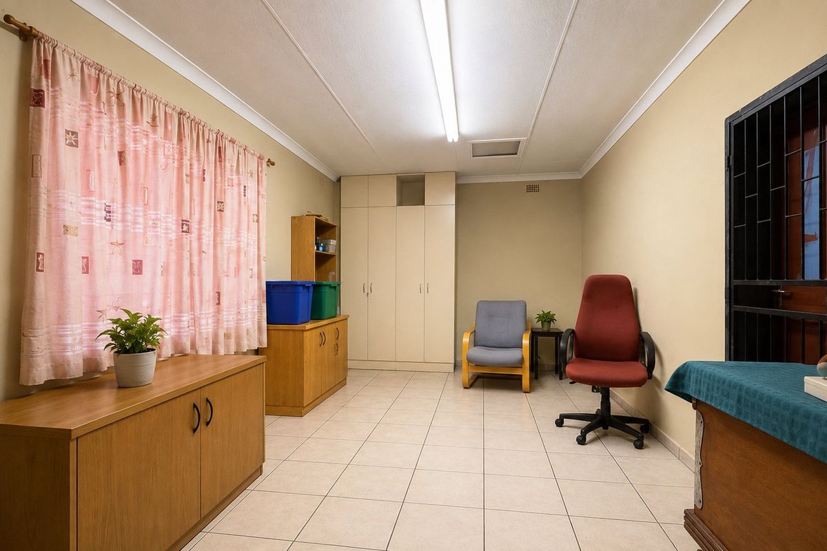 A functional bedroom featuring tiled flooring, built-in cupboards, and a secure entrance gate, offering a neutral space ready for personalization.