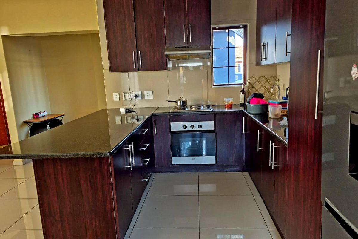 A functional kitchen featuring dark wood cabinetry, granite countertops, built-in oven, gas hob, and tiled flooring.
