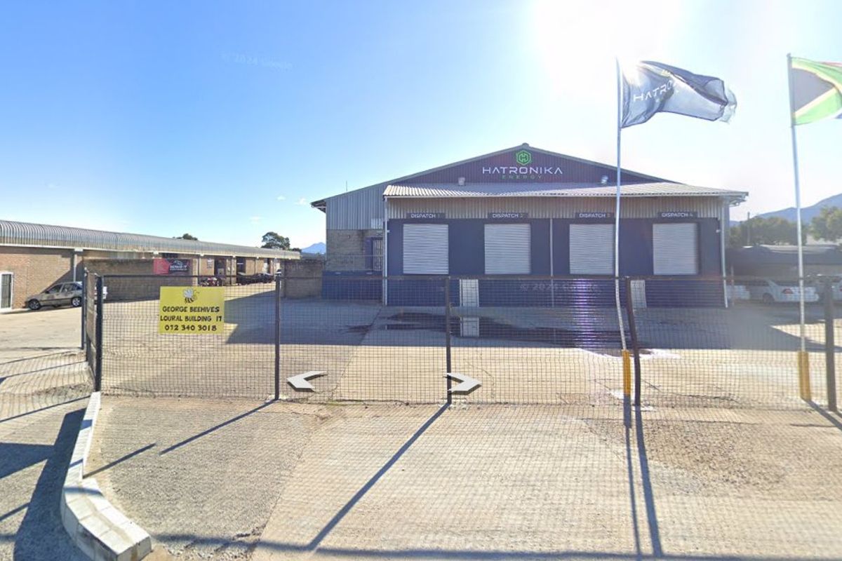 Industrial facility featuring multiple roller shutter dispatch doors, metal cladding, and a secure fenced yard area.