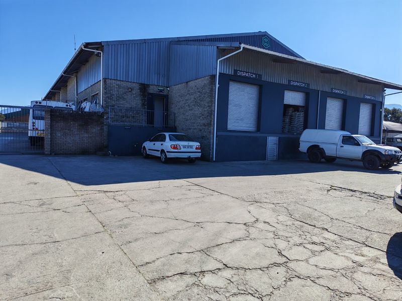 Industrial warehouse exterior featuring multiple dispatch roller shutter doors and a large concrete yard area.